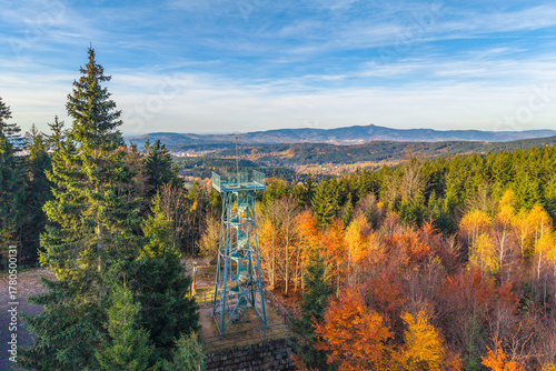 Explore the historic Slovanka Lookout Tower in the Jizera Mountains, surrounded by vibrant autumn foliage. This is the oldest iron tower in the Czech Republic, offering stunning views.