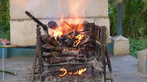 Hindu outdoor funeral pyre burning on wooden bier at rural cremation ground in India