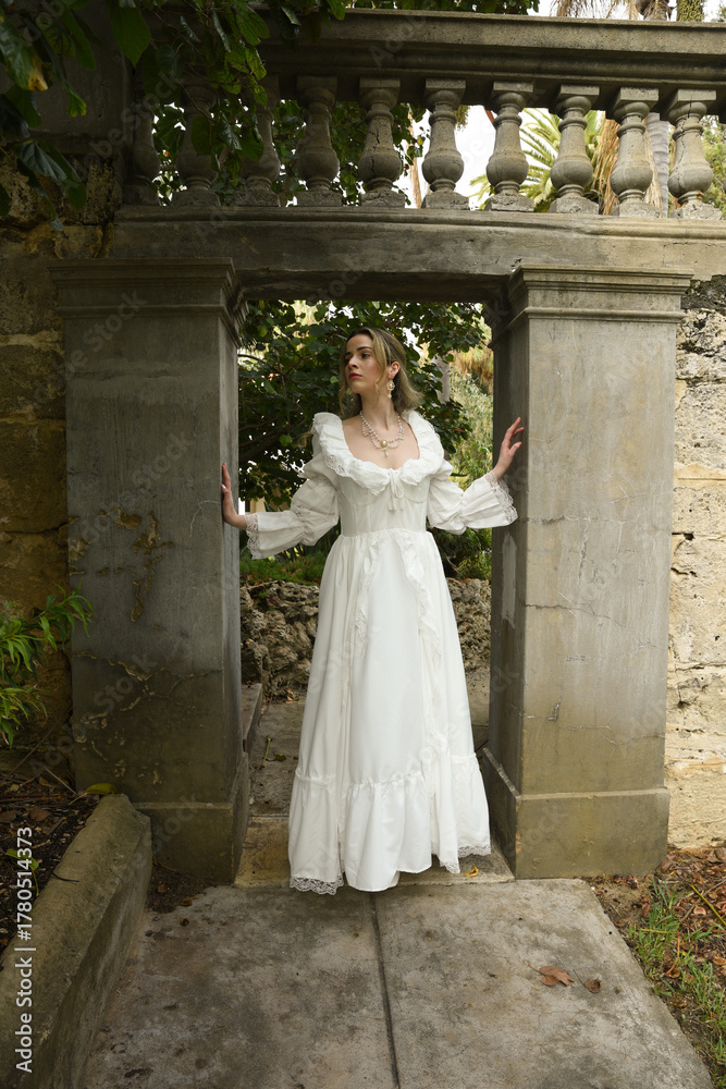 Obraz premium Full length female figure of beautiful blonde model wearing white fantasy wedding gown. walking through doorway of historical fairytale castle location 
