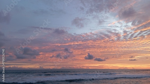 Vibrant sunset over the ocean with dramatic pink and orange altocumulus clouds creating a breathtaking, beautiful, and peaceful natural scene
