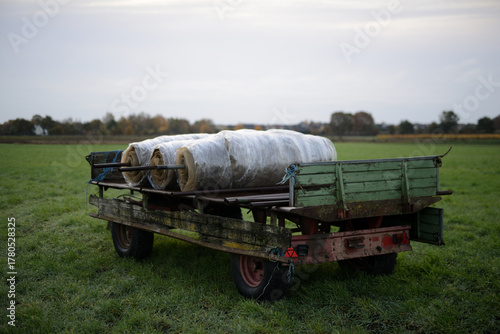 Gummiwagen auf einer Ackerbaufläche der Landwirtschaft einer Herbstlandschaft im faden, natürlichen Morgenlicht.