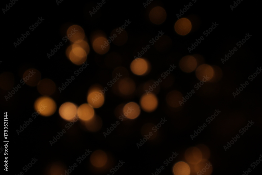 Obraz premium Golden blurred bokeh lights on black background. Glitter sparkle stars for celebrate. Overlay for your design. Bokeh effect golden light background. Golden Christmas concept. yellow sparkling bokeh