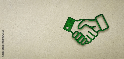 Concept of environmental cooperation and agreement approved deal. Green business handshake icon on brown paper background with copy space.
