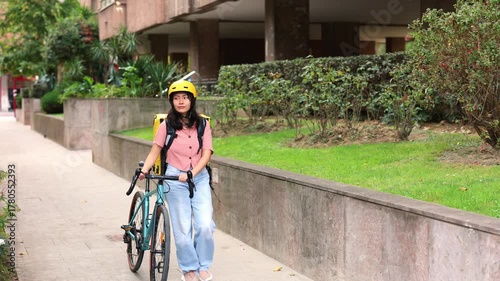 Asian delivery courier walking with bicycle and thermal bag in the city