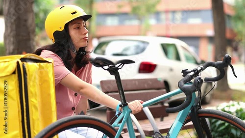 Delivery woman resting on a park bench next to her bicycle