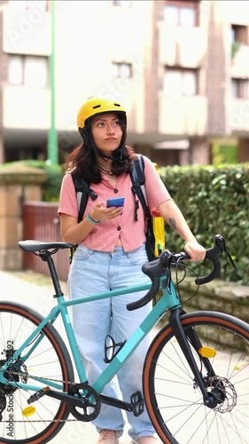 vertical Asian female courier with bicycle checking address on smartphone