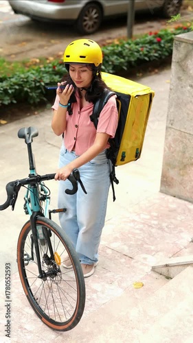 vertical Asian food delivery courier speaking on smartphone