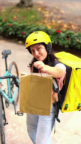 vertical Asian delivery woman giving a paper bag to a client