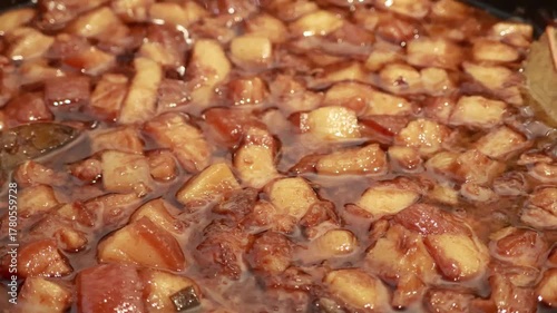 Stirring and pouring braised pork belly meat over cooked rice.