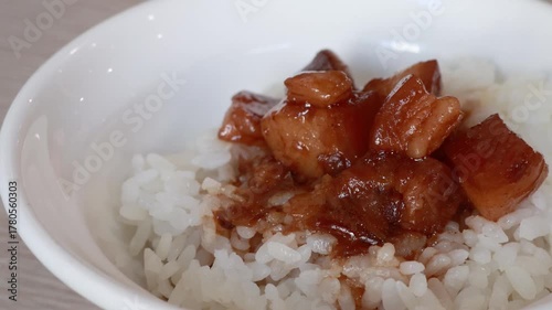 Stirring and pouring braised pork belly meat over cooked rice.