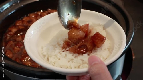 Stirring and pouring braised pork belly meat over cooked rice.