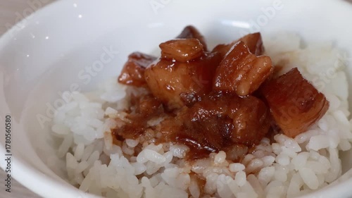 Stirring and pouring braised pork belly meat over cooked rice.