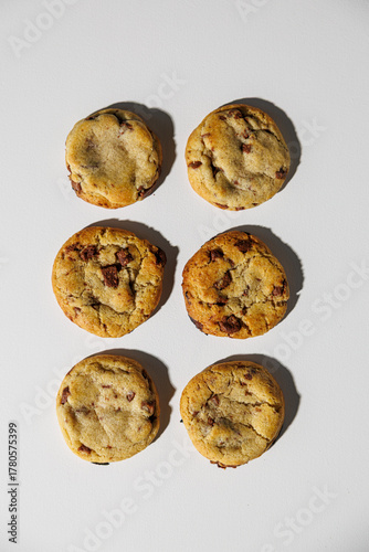 A set of six golden-brown chocolate chip cookies arranged in two neat columns on a clean white surface. No visible logos or branding