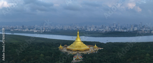 Aerial view of the golden Global Vipassana Pagoda gleaming against the backdrop of the cityscape and calm waters, Mumbai, Maharashtra, India.