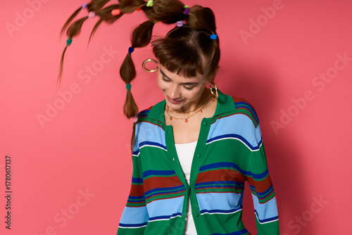 Bilde på lerret Stylish young woman joyfully poses with playful hairstyle against a vibrant pink