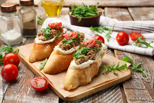 Cuadro en lienzo Delicious bruschettas with tuna, cream cheese and tomatoes on wooden table, clos