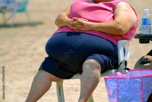 Behang Very Overweight or obese   woman sitting in a chair on a beach In Venice FL