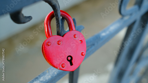 Red heart-shaped love lock on metal railing symbolizing affection and romance