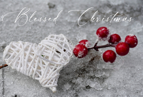 Blessed Christmas greeting card - white heart and red Christmas decoration on ice background with greetings