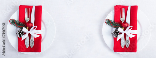 Christmas setting the table with red napkin on the white plate on a white tablecloth. Top view. Copy space.