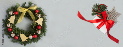 Christmas wreath and gift box on a gray background. Copy space. Top view.