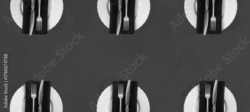 Setting the table with black napkin on the white plate on gray background. Top view. Copy space. Pattern.