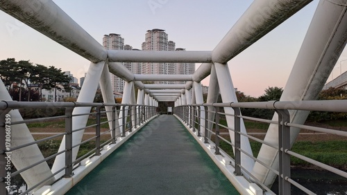 Photos Modern pedestrian bridge with geometric structure leading toward city buildings