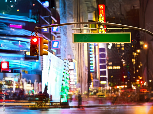 Blank sign and red stop light in a modern city at night
