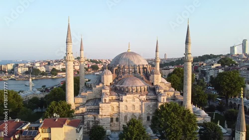 Sweeping cinematic video of Süleymaniye Mosque at golden hour, its dome & minarets overlooking Istanbul cityscape with terracotta rooftops. Concept of historical grandeur