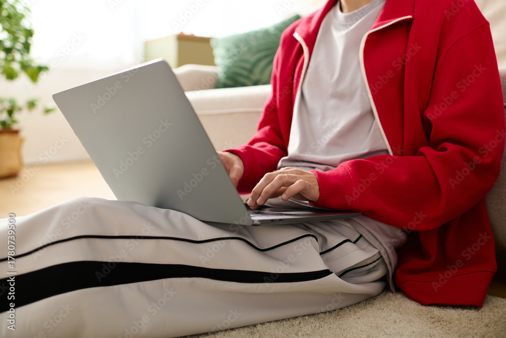 Naklejka premium Stylishly dressed man relaxes while working on a laptop in a cozy indoor setting
