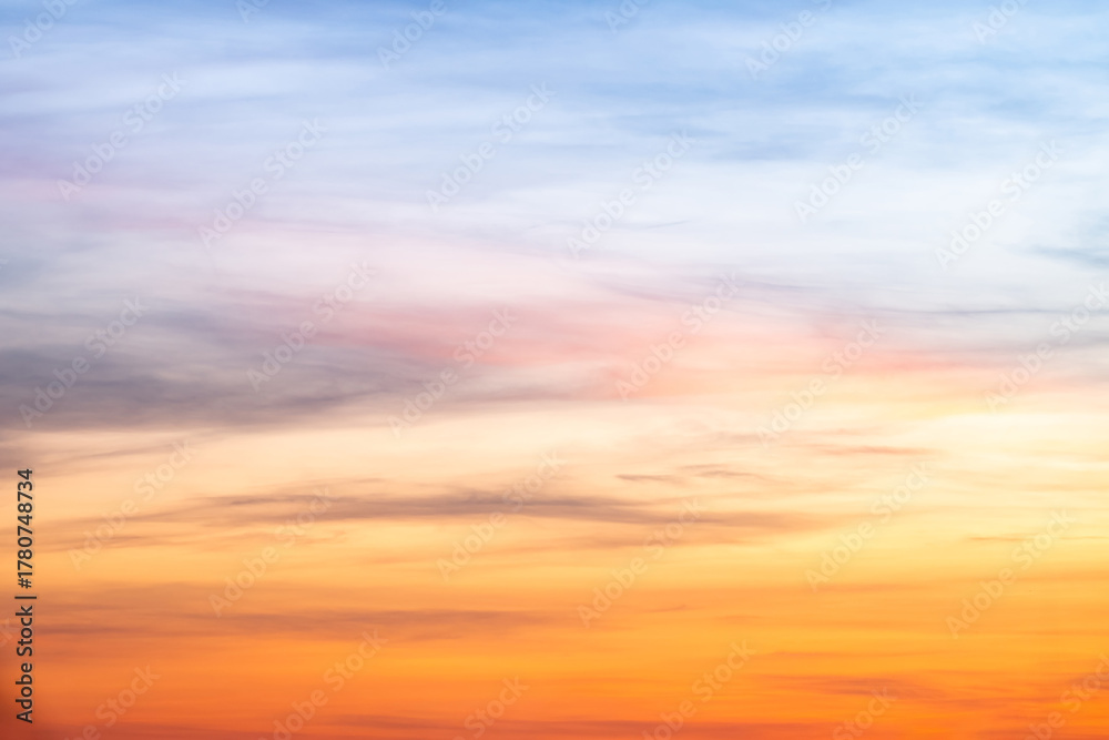 Fototapeta premium Sunset or sunrise sky with a vibrant gradient of orange, gold, and soft blue. Clear atmosphere with wispy clouds. Peaceful, natural light background. hope, freedom, new day and inspirational Concepts