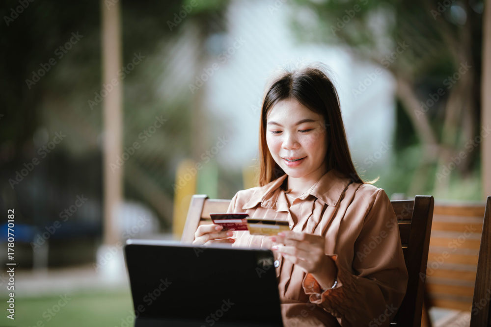 Fototapeta premium A woman uses her smartphone, smiling as she shops online, capturing a moment of modern digital lifestyle and mobile finance.