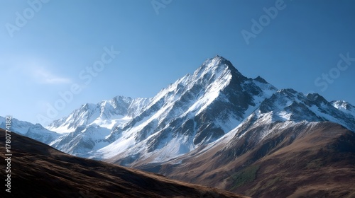 Fototapeta Naklejka Na Ścianę i Meble -  Majestic snow covered mountain peaks dominate a vast landscape under a clear brilliant blue sky