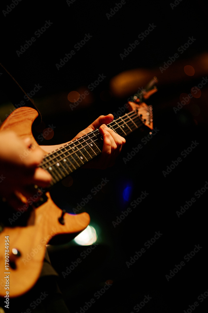Naklejka premium Close up look of a man playing the electric guitar during a concert, no faces are shown, shallow depth of field
