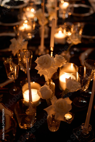 Luxurious setting of dark restaurant tables with candles and fresh flowers