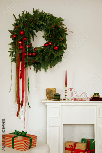 Minimalist Christmas interior with a green wreath, red ribbons, and festive gifts. Warm and elegant holiday styling.