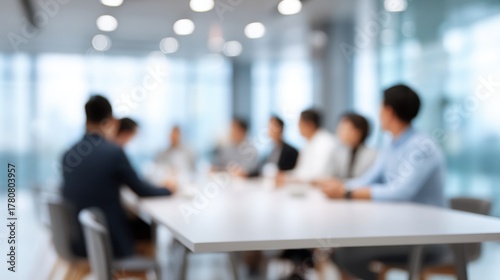 Blurry meeting scene with professionals gathered around a conference table.