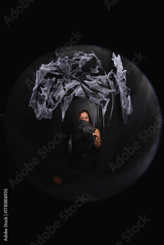 portrait of a young witch in hat on black background with spider net