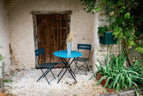 Cozy Outdoor Cafe Table Set With Blue Metal Table And Chairs Beside Rustic Doorway
