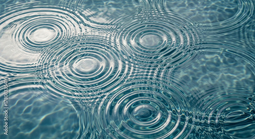 Ripples on the surface of water created by raindrops impacting the water creating concentric circles
