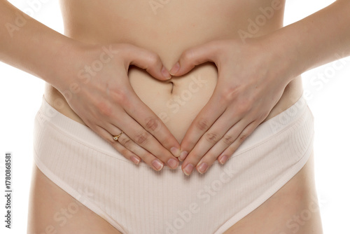 Wallpaper Mural Studio shot of woman’s torso with hands making heart shape over belly, symbolizing happiness or pregnancy, on white background. Torontodigital.ca