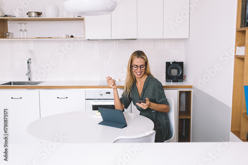 Fotografía Modern freelancer smiling during remote call, working with tablet at clean kitch