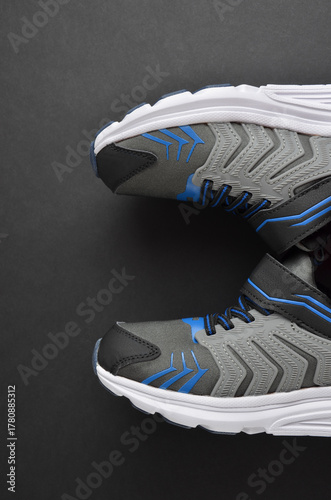 Sports sneakers in gray with blue tabs on a black background.