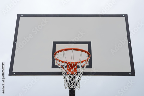 basketball backboard with a hoop and net against a sky