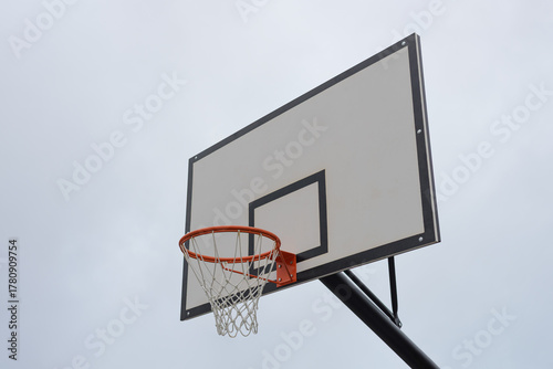 basketball backboard with a hoop and net against a sky