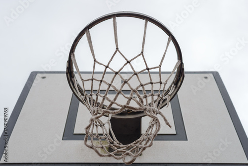 basketball backboard with a hoop and net against a sky