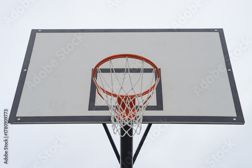 basketball backboard with a hoop and net against a sky