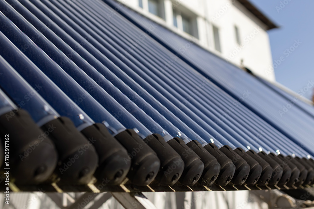 Fototapeta premium A close-up view of an evacuated tube solar water heater collector. This innovative system, angled towards the sun, represents clean energy, sustainability, and energy-saving technology.