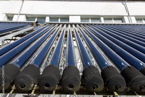 A close-up view of an evacuated tube solar water heater collector. This innovative system, angled towards the sun, represents clean energy, sustainability, and energy-saving technology.