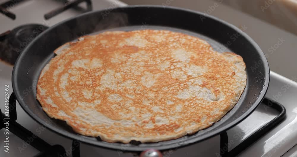 custom made wallpaper toronto digitalA golden-brown pancake cooking in a black frying pan on a gas stove. The pancake has a smooth texture and is evenly cooked.